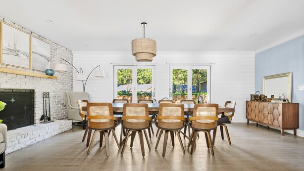 A dining area with a brick wall, a fireplace, and a large window. - The Molasses Manor | Minutes from Everything (Mt Pleasant)