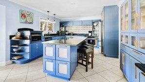 A kitchen with blue cabinets, a central island, and a window. - The Molasses Manor | Minutes from Everything (Mt Pleasant)