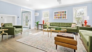 A spacious living room with a green sofa set, a coffee table, and a ceiling fan. - The Molasses Manor | Minutes from Everything (Mt Pleasant)