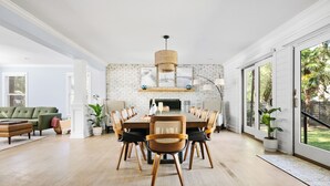 A spacious dining area with a brick wall, a chandelier, and a large window. - The Molasses Manor | Minutes from Everything (Mt Pleasant)