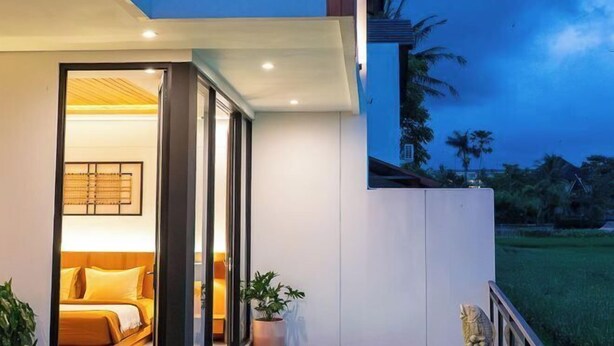 A modern hotel room with a bed, a potted plant, and a view of the outdoors. - Paz Tropical Villa Ubud by Omkara Experience (Bali)