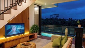 A modern living room with a flat-screen TV, a sofa, a coffee table, and a staircase. - Paz Tropical Villa Ubud by Omkara Experience (Bali)