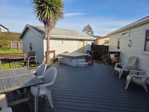 A deck with outdoor furniture, a hot tub, and a statue. - Stroll to the Beach! Warm up in the Hot Tub (Brookings)