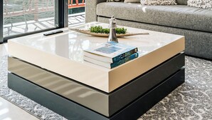 Un salon moderne avec un canapé, une table basse en verre et une vue sur la verdure à l’extérieur.