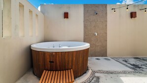 Un espace de détente avec un bain à remous en bois, un banc et un sol carrelé.