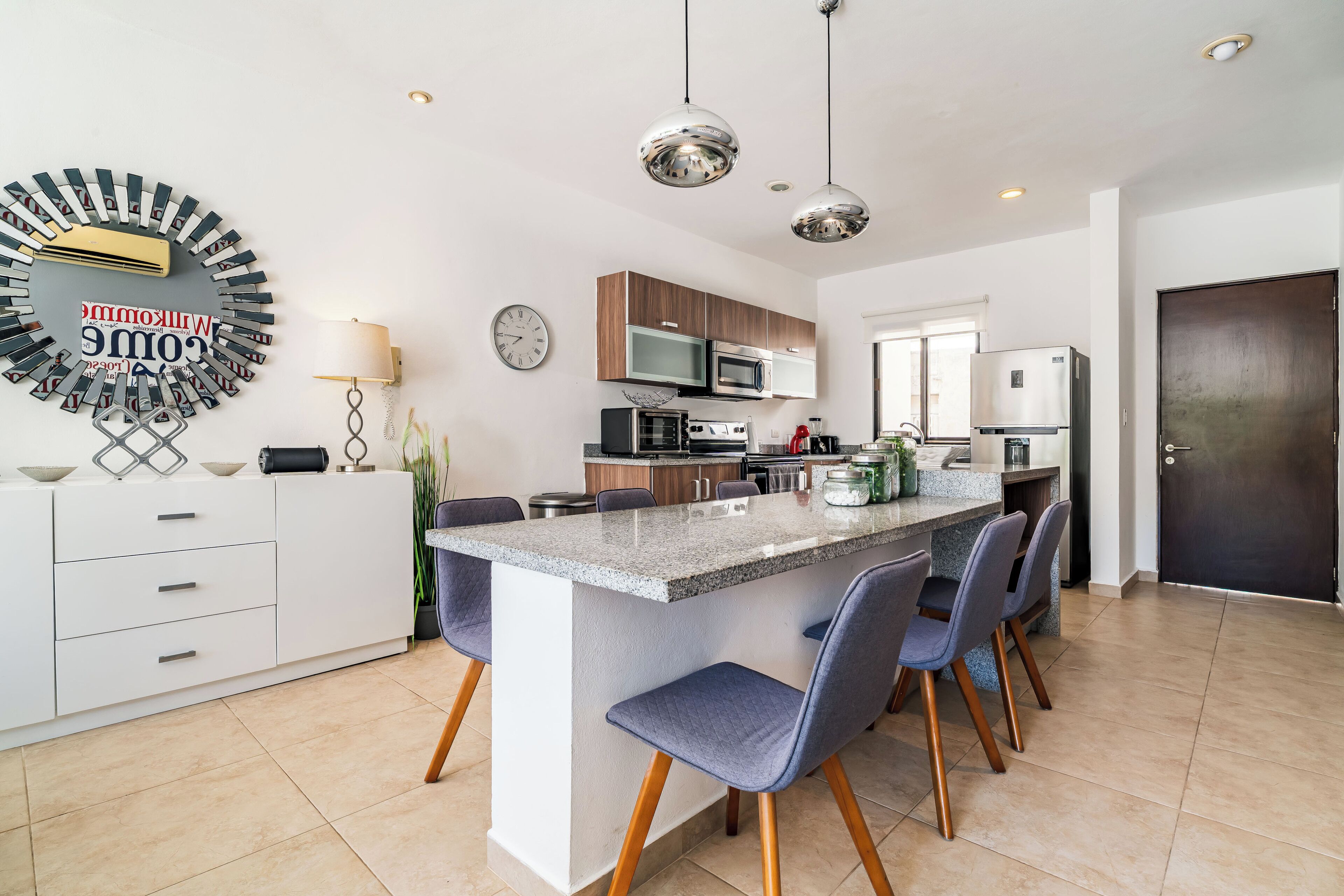 A modern kitchen with a central island, built-in appliances, and pendant lighting.