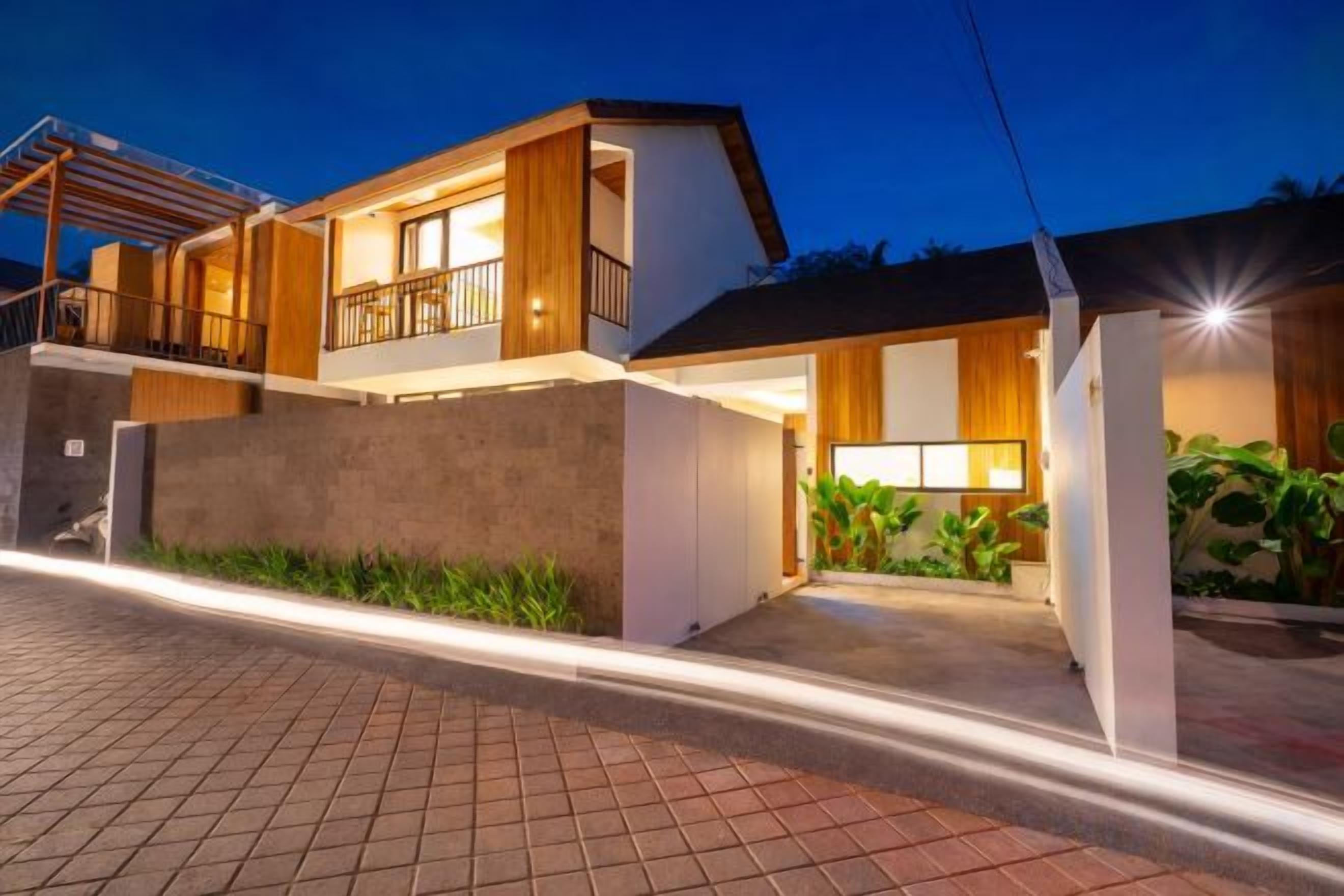 Une maison moderne à deux étages, dotée d’un balcon, d’un garage et d’une entrée bien éclairée.
