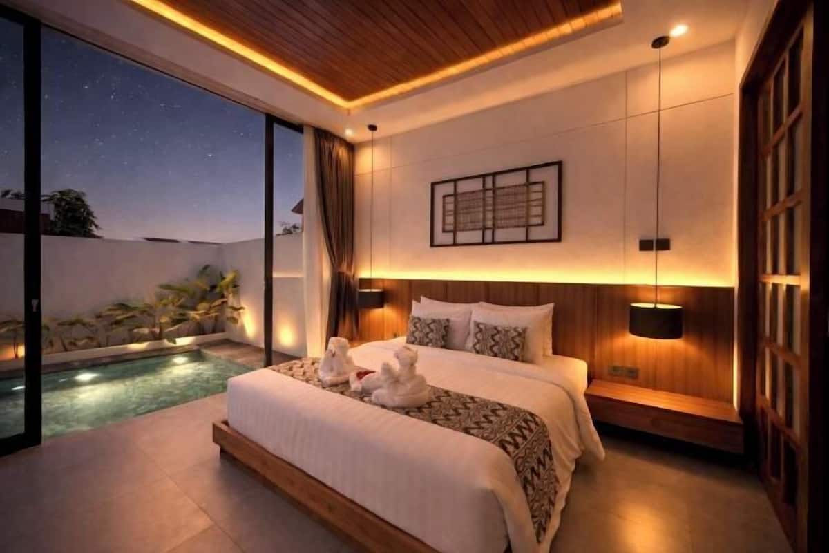 Een moderne slaapkamer met een groot bed, bedlampen, uitzicht op de lucht en een klein zwembad.
