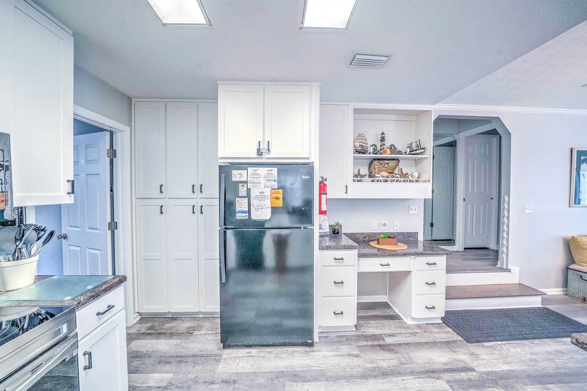 Una cocina moderna con armarios blancos, un refrigerador de acero inoxidable y una encimera de granito.