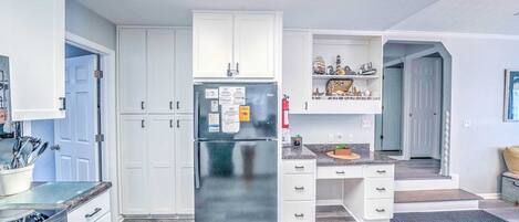 Una cocina moderna con armarios blancos, un refrigerador de acero inoxidable y una encimera de granito.