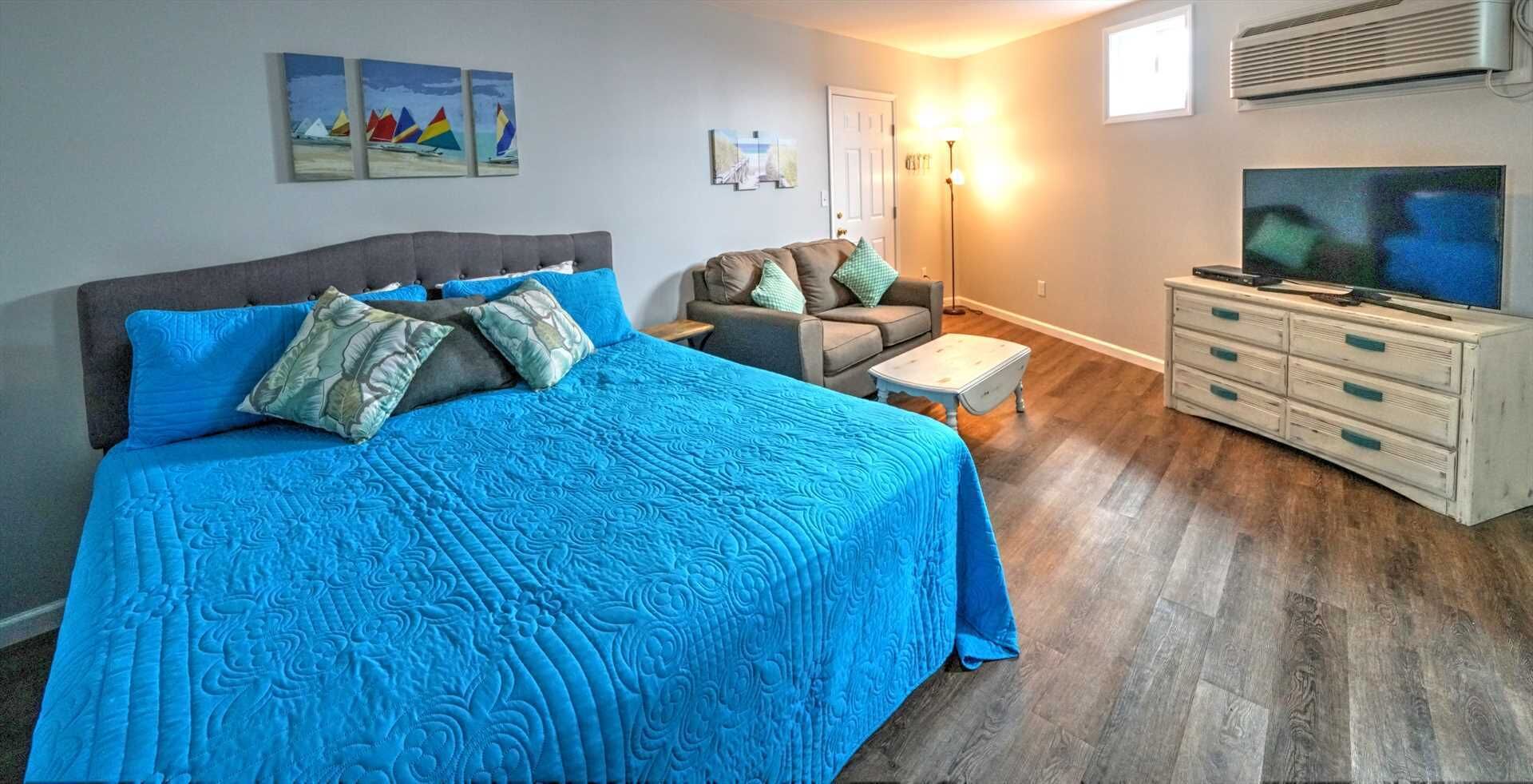 A bedroom with a large bed, a sofa, a TV, and artwork on the walls.