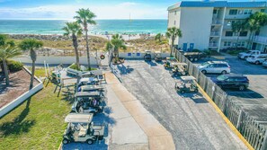 Ein Parkplatz mit Golfcarts, Blick auf den Strand und ein Gebäude mit Balkonen.
