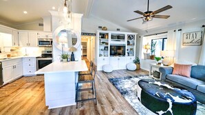 A modern kitchen with white cabinetry, a central island, and a ceiling fan. - 204 Squid Lane - Adorable Beach House! 3 Bedroom 2 baths - Golf Cart included! (Panama City Beach)