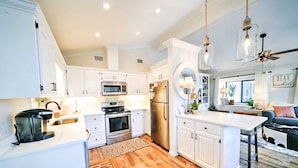 A modern kitchen with white cabinetry, stainless steel appliances, and a wooden floor. - 204 Squid Lane - Adorable Beach House! 3 Bedroom 2 baths - Golf Cart included! (Panama City Beach)
