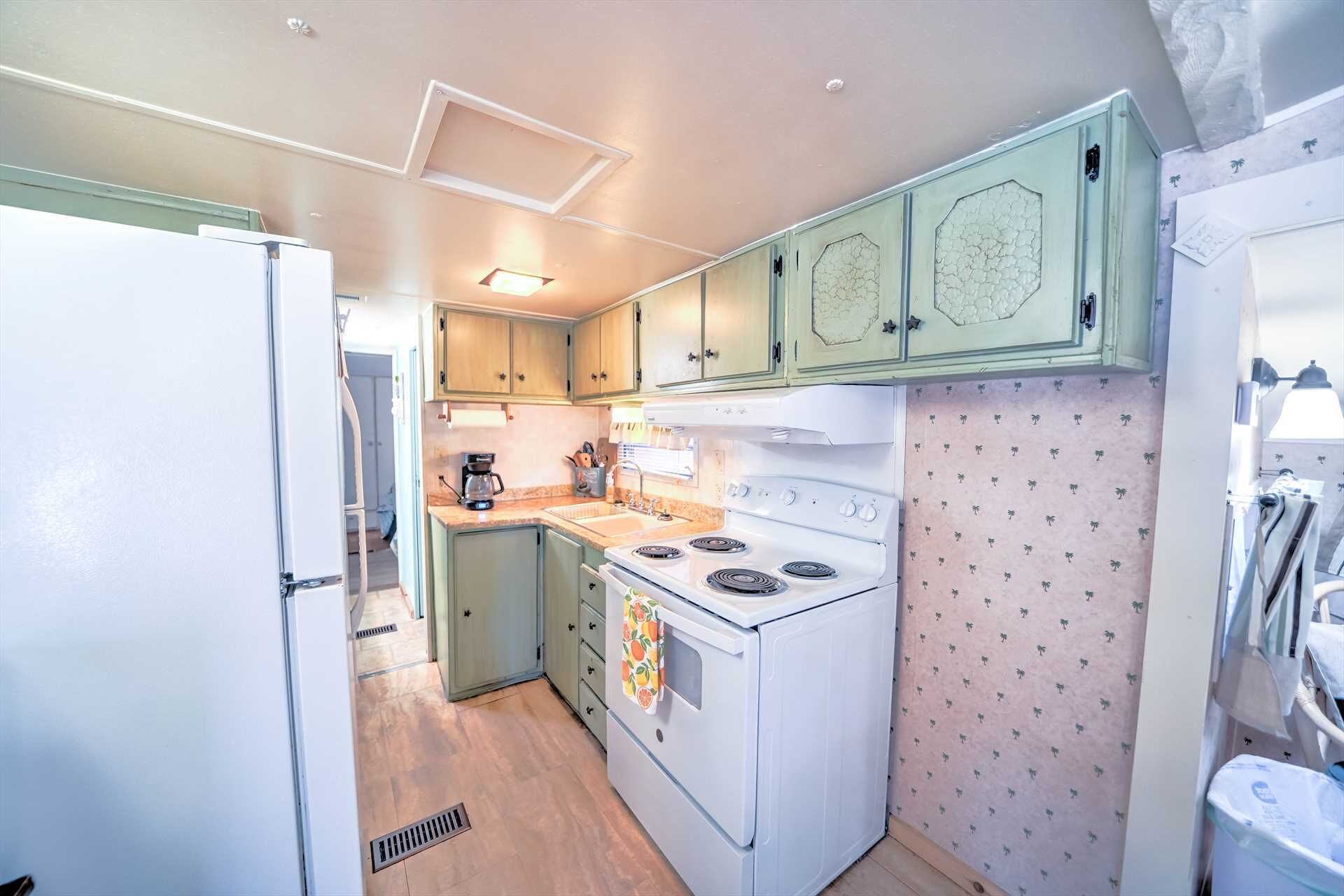 Una cocina compacta con armarios verde claro, una estufa blanca y un salpicadero con diseño.