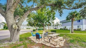 A patio area with outdoor furniture, a large tree, and a building in the background. - Perfect Punta Gorda Location Resort Pool & Harbor (Port Charlotte)