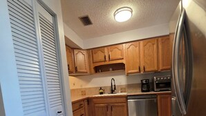 A kitchen with wooden cabinets, a stainless steel refrigerator, a dishwasher, and a coffee maker. - Perfect Punta Gorda Location Resort Pool & Harbor (Port Charlotte)