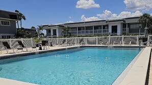 A rectangular swimming pool with a tiled edge, surrounded by lounge chairs and a white fence. - Perfect Punta Gorda Location Resort Pool & Harbor (Port Charlotte)
