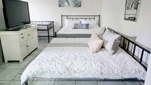Une chambre avec deux lits, un téléviseur posé sur une commode et des œuvres d’art accrochées aux murs.