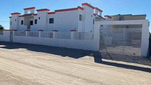 Un bâtiment moderne de couleur blanche, agrémenté de touches de rouge, doté d’une entrée sécurisée et surplombant un ciel dégagé.