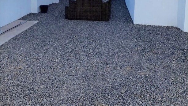 Un espace patio extérieur moderne, doté d’un coin salon, de murs blancs et offrant une vue dégagée sur l’océan.