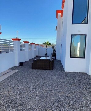 Ein moderner Außenbereich mit Sitzgelegenheit, weißen Wänden und freiem Blick auf das Meer.