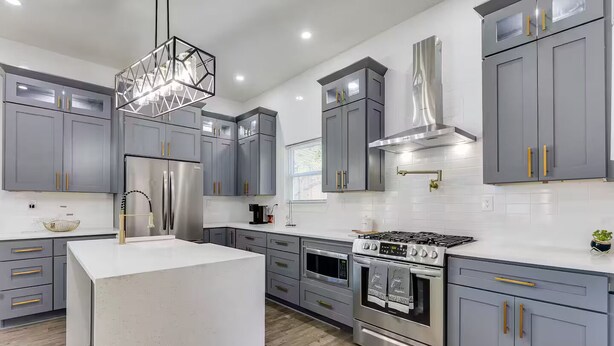 A modern kitchen with grey cabinets, stainless steel appliances, and a central island. - 4 bed New Construction Home near airport/downtown (Atlanta)