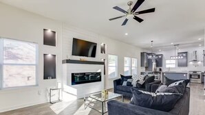 A modern living room with a fireplace, a sofa, a coffee table, and a TV mounted on the wall. - 4 bed New Construction Home near airport/downtown (Atlanta)