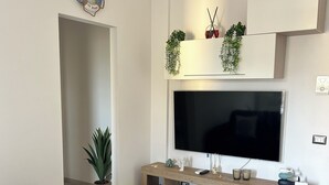 Una sala de estar moderna con un sofá gris, un televisor de pantalla plana montado en un mueble de madera y un reloj de pared.