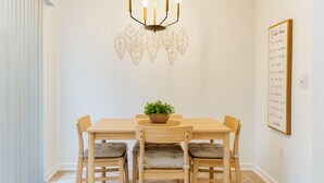 A dining area with a wooden table, four chairs, a chandelier, a wall-mounted plant, and a framed quote on the wall. - Peaceful 2-bedroom townhome with AC in Lawrenceville (Lawrenceville)