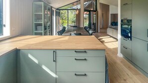 A modern kitchen with a wooden countertop, light-colored cabinets, and a view of the outdoors.
