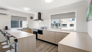 A modern kitchen with a central island, built-in appliances, and large windows with a view of the city. - Trade Winds Unit 5, 52 Edmund St, Kings Beach (Kings Beach)