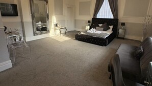 Un dormitorio espacioso con una cama grande, un candelabro, un espejo y un televisor.