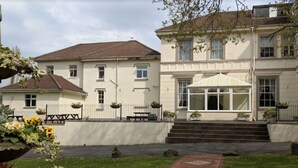 Un edificio de dos pisos con un porche cubierto y un jardín con un sendero de ladrillo.