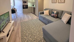 A modern living room with a grey sofa, patterned rug, and a flat-screen TV. - Aconchego da Vila | Olival Flat | Castelo de Vide (Castelo de Vide)