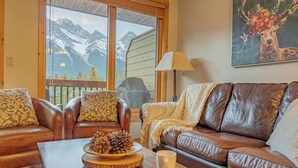 Una sala de estar acogedora con sofás de cuero, una mesa de centro de madera y un ventanal con vistas a la montaña.