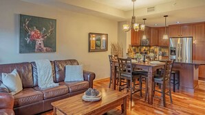 Una cocina moderna con armarios de madera, electrodomésticos de acero inoxidable y una zona de comedor con mesa y sillas de madera.