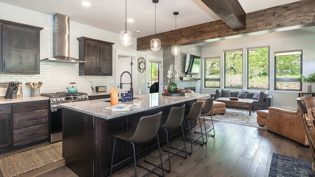 A modern kitchen with a large island, dark cabinetry, and a built-in stove. - Trailside Location | Mountain Escape (Granby)