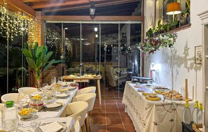 An indoor dining area with tables set for a meal, a large window with curtains, and indoor plants. - Luxurious home in Mijas (Mijas)