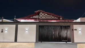 A building with a large, dark entrance door, a tiled roof, and a moon in the sky.