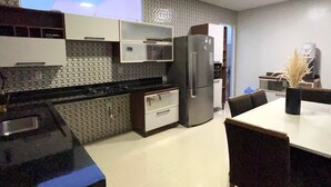 A modern kitchen with a dining area, featuring a refrigerator, stove, and cabinets.