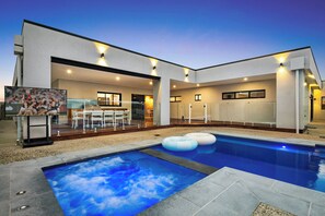 A modern house with a swimming pool, outdoor seating, and a large TV screen. - Luxury Bellbrae Retreat w  Pool, Spa & 12 Guests (Bellbrae)