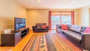 A living room with a dark leather sofa, a black leather couch, a TV on a wooden stand, and a patterned rug. - Mountain View Retreat, Year Round Sunshine
1 bed, 1 renovated bath in Boulder (Boulder)