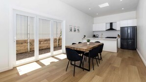 Eine moderne Küche mit weißen Schränken, einem schwarzen Kühlschrank und einem Holzespeise Tisch mit Stühlen.