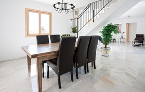 Ein großzügiger Essbereich mit Holztisch, schwarzen Stühlen, einer Treppe und Topfpflanzen.