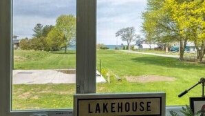 Une vue depuis une fenêtre, sur laquelle on peut lire l’inscription « LAKEHOUSE », qui indique le nom de la propriété.