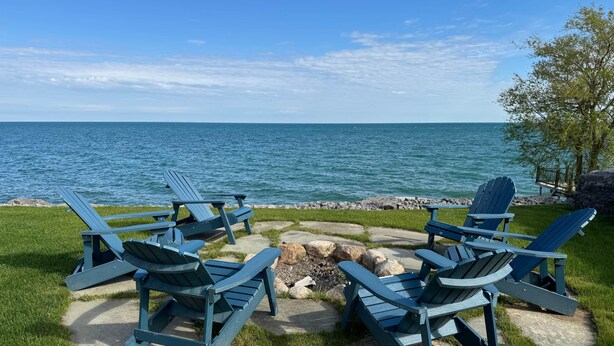 Un espace de détente aménagé au bord du lac, avec des fauteuils Adirondack et un foyer en pierre.