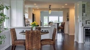 Un espace repas avec une table ronde et quatre chaises, un coin cuisine avec un plan de travail et une vue sur l’extérieur.