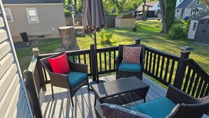 A deck with wicker furniture and cushions, surrounded by a wooden deck and a view of a backyard. - LVR's 3 Sister's Cape (Lewiston)
