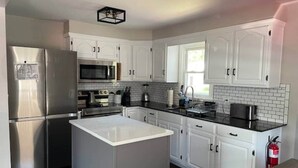 A modern kitchen with white cabinets, stainless steel appliances, and a central island. - LVR's 3 Sister's Cape (Lewiston)